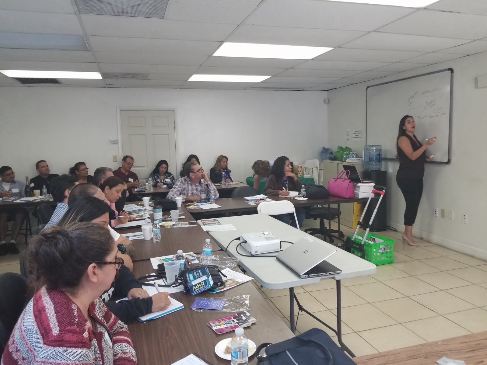 Juliana explicando frente al pizarrón a un grupo de asistentes