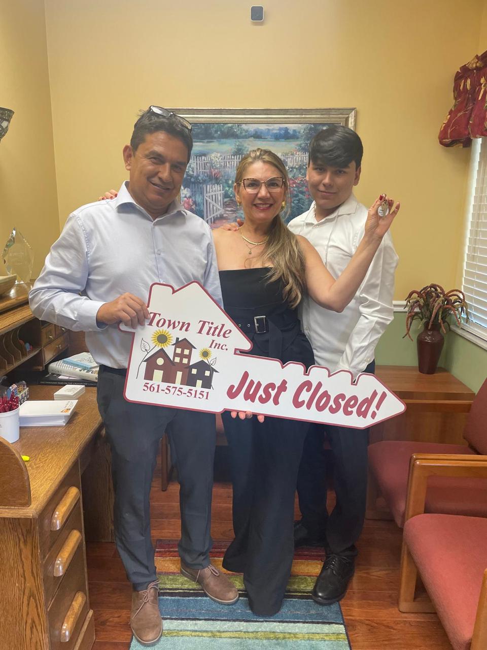 Familia celebrando su cierre con cartel Just Closed de Town Title